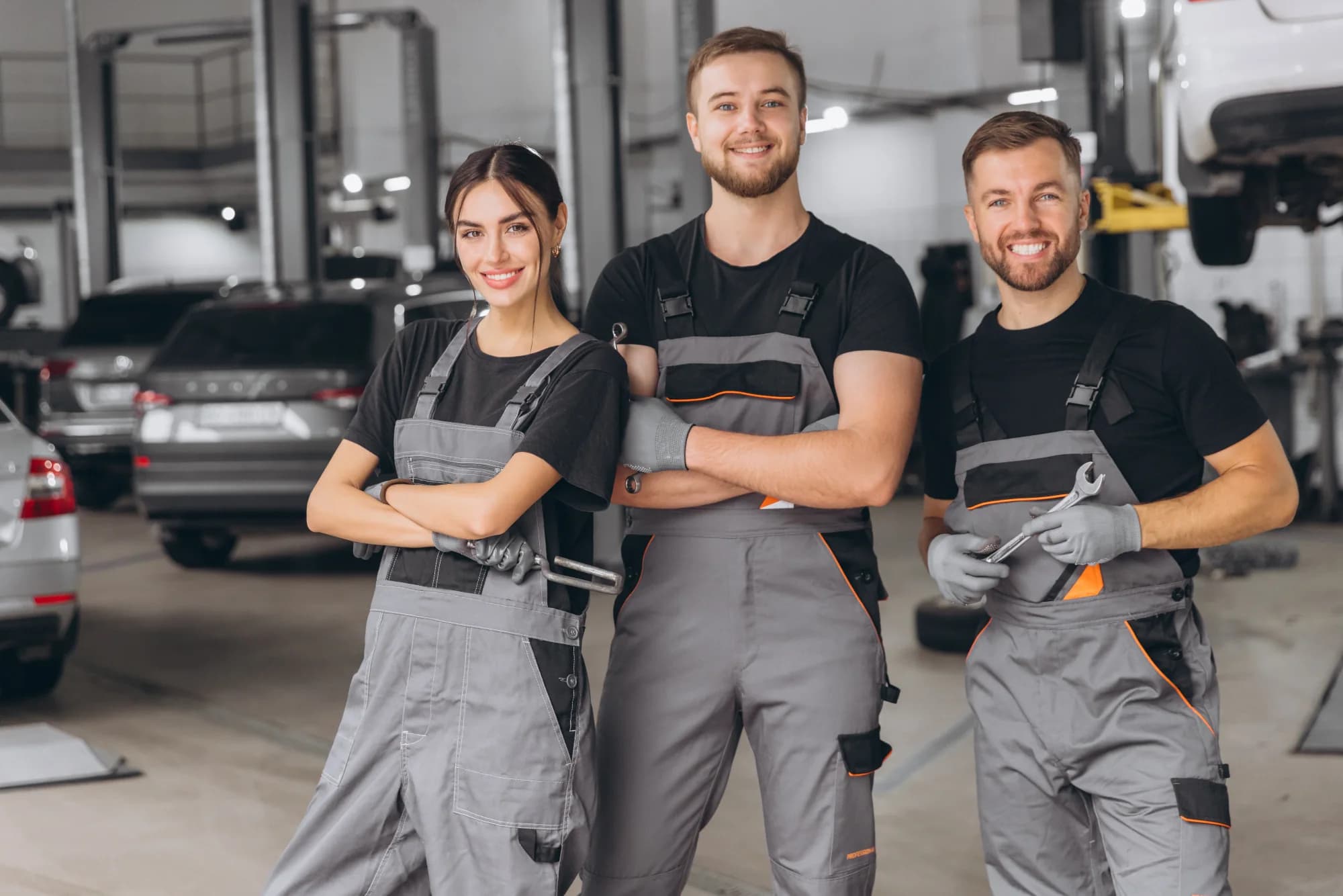 Drei freundlich lächelnde Kfz-Fachkräfte in einer Werkstatt
